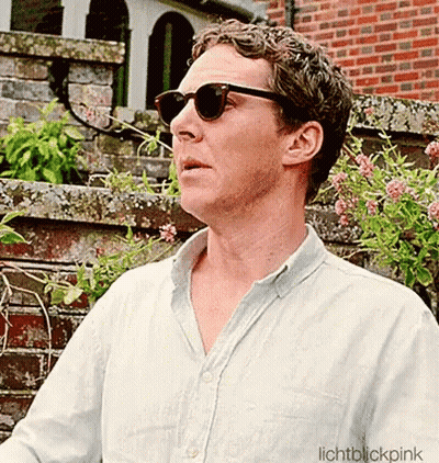 A Man Wearing Sunglasses Is Standing In Front Of A Brick Building GIF