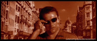 A Man Wearing Sunglasses Is Standing In Front Of A Building That Says Bp Platters GIF