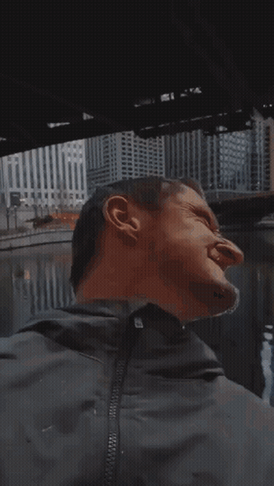 A Man Wearing Sunglasses Is Standing In Front Of A City Skyline . GIF