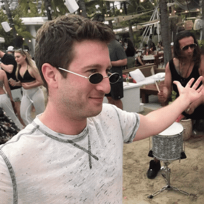 A Man Wearing Sunglasses Is Standing In Front Of A Drum GIF