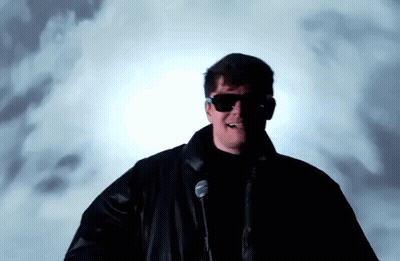 A Man Wearing Sunglasses Is Standing In Front Of A Microphone . GIF
