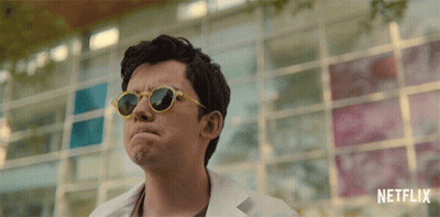 A Man Wearing Sunglasses Is Standing In Front Of A Netflix Logo GIF