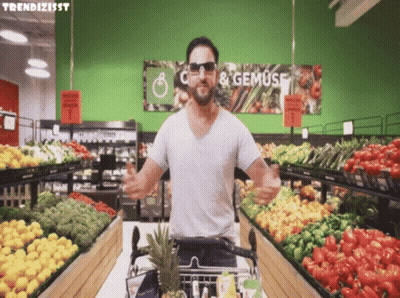 A Man Wearing Sunglasses Is Standing In Front Of A Sign That Says " C & Gemuse " GIF