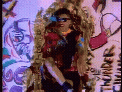 A Man Wearing Sunglasses Is Standing In Front Of A Wall With Graffiti That Says Thunder GIF