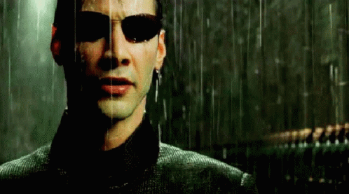 A Man Wearing Sunglasses Is Standing In The Rain And Looking At The Camera . GIF