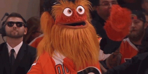 A Man Wearing Sunglasses Is Taking A Picture Of A Mascot In The Crowd GIF