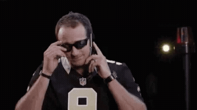 A Man Wearing Sunglasses Is Talking On A Cell Phone In A Dark Room . GIF