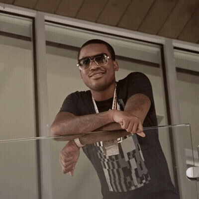 A Man Wearing Sunglasses Leans On A Glass Railing With His Arm Resting On His Elbow GIF