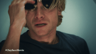 A Man Wearing Sunglasses Looks Through Binoculars With #Clayfacemovie Written Below Him GIF