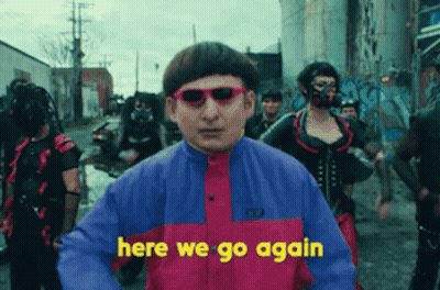 A Man Wearing Sunglasses Says Here We Go Again In Front Of A Crowd Of People GIF