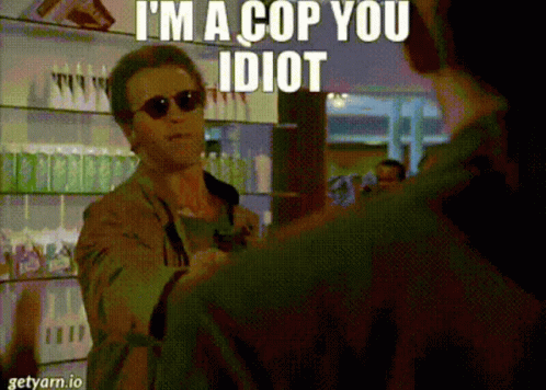 A Man Wearing Sunglasses Says I 'M A Cop You Idiot While Talking To Another Man GIF