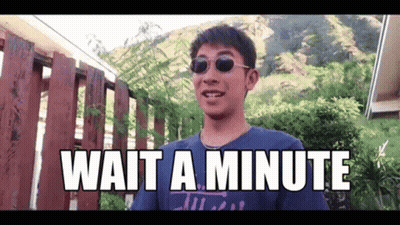 A Man Wearing Sunglasses Says Wait A Minute In Front Of A Wooden Fence GIF