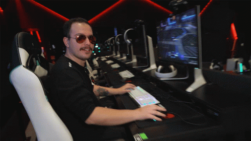 A Man Wearing Sunglasses Sits In Front Of A Computer Monitor GIF