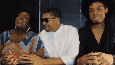 A Man Wearing Sunglasses Sits Next To A Woman In A Striped Shirt GIF