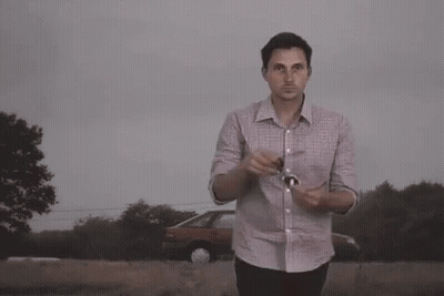 A Man Wearing Sunglasses Stands In Front Of A Large Explosion GIF