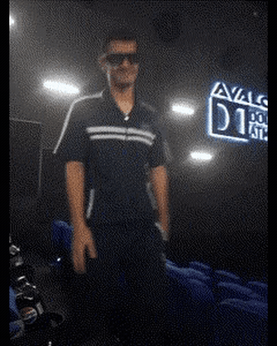 A Man Wearing Sunglasses Stands In Front Of A Sign That Says Avals GIF