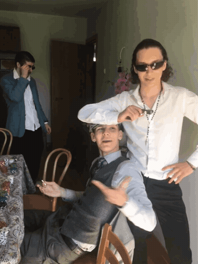 A Man Wearing Sunglasses Stands Next To Another Man GIF