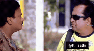 A Man Wearing Sunglasses Talks To Another Man In A Yellow Shirt That Says ' Ttilisathi ' On It GIF