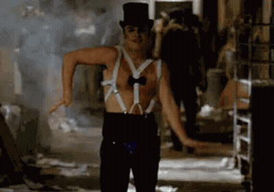 A Man Wearing Suspenders And A Top Hat Is Dancing In A Room . GIF