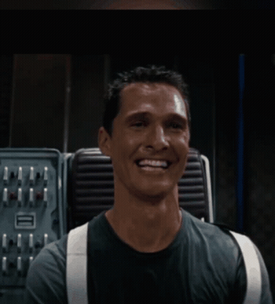 A Man Wearing Suspenders Is Smiling In Front Of A Machine GIF