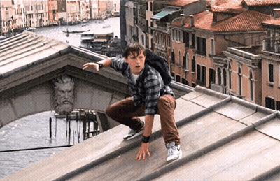 A Man With A Backpack Is Crawling On The Roof Of A Building Overlooking A City GIF