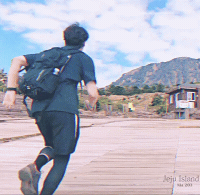 A Man With A Backpack Is Running On A Boardwalk With The Words Jeju Island Written On It GIF