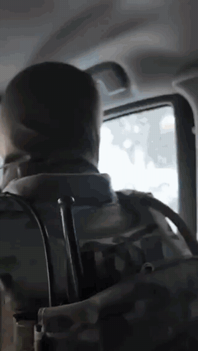 A Man With A Backpack Is Sitting In The Back Seat Of A Car Looking Out The Window GIF