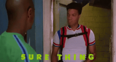 A Man With A Backpack Is Standing Next To Another Man With The Word Sure Thing Written On The Wall Behind Him GIF
