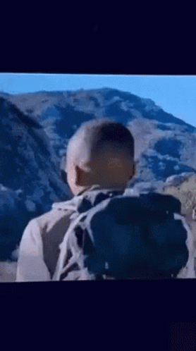 A Man With A Backpack Is Walking Through A Mountain Range . GIF