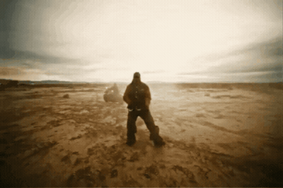 A Man With A Backpack Stands In A Desert GIF