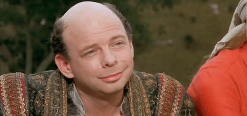 A Man With A Bald Head And A Red Shirt Is Smiling For The Camera GIF