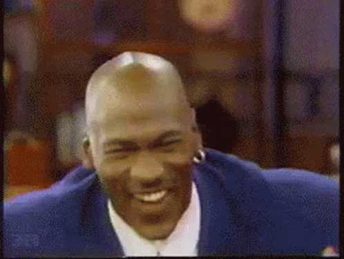 A Man With A Bald Head Is Smiling And Wearing Earrings GIF