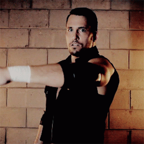 A Man With A Bandage On His Arm Is Pointing At Something GIF