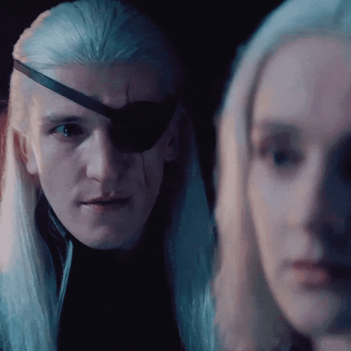 A Man With A Bandage On His Eye Looks At A Woman In A Dark Room GIF