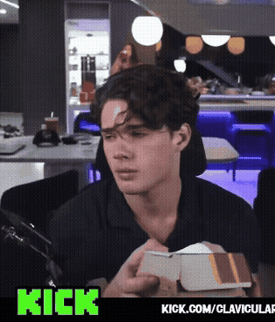 A Man With A Bandage On His Forehead Is Holding A Box With The Words Kick.com/clavicular Below Him GIF