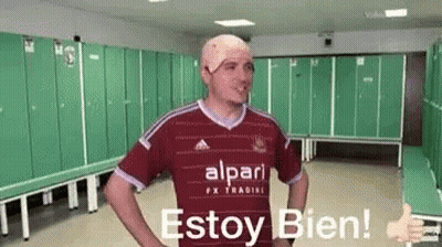 A Man With A Bandage On His Head Is Giving A Thumbs Up In A Dressing Room . GIF