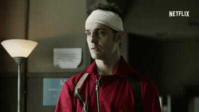 A Man With A Bandage On His Head Is Standing In Front Of A Sign That Says Netflix On It GIF