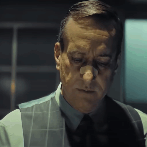 A Man With A Bandage On His Nose Is Wearing A Vest And Tie GIF