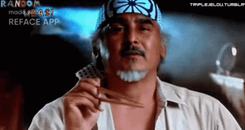 A Man With A Bandana On His Head Is Holding A Pair Of Scissors And A Card . GIF