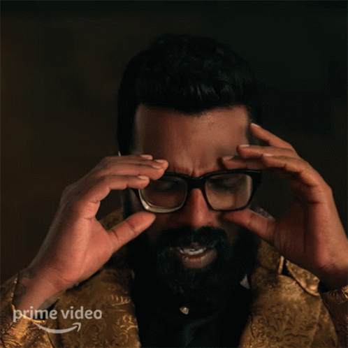A Man With A Beard Adjusts His Glasses With A Prime Video Logo In The Corner GIF