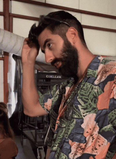 A Man With A Beard Adjusts His Sunglasses In Front Of A Cinelease Sign GIF