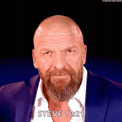 A Man With A Beard And A Bald Head Is Wearing A Blue Suit And A White Shirt . GIF