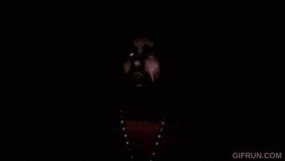 A Man With A Beard And A Beanie Is Wearing A Yellow Shirt And Necklace . GIF