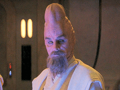 A Man With A Beard And A Big Head Is Standing In A Room GIF