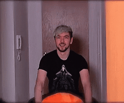 A Man With A Beard And A Black Shirt Is Standing In A Doorway . GIF