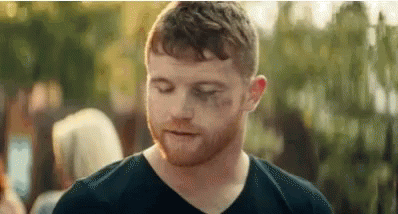 A Man With A Beard And A Black Shirt Is Standing In Front Of A Crowd . GIF