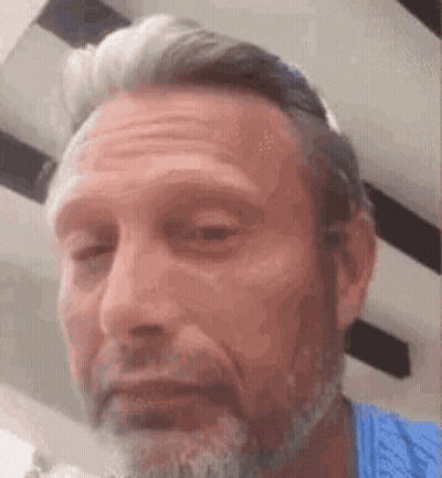 A Man With A Beard And A Blue Shirt Is Making A Face . GIF
