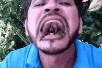 A Man With A Beard And A Blue Shirt Is Making A Funny Face . GIF