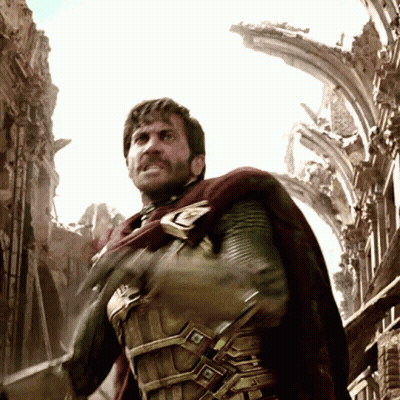 A Man With A Beard And A Cape Is Standing In Front Of A Ruined Building GIF