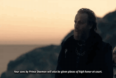 A Man With A Beard And A Chain Around His Neck Is Standing On Top Of A Hill . GIF